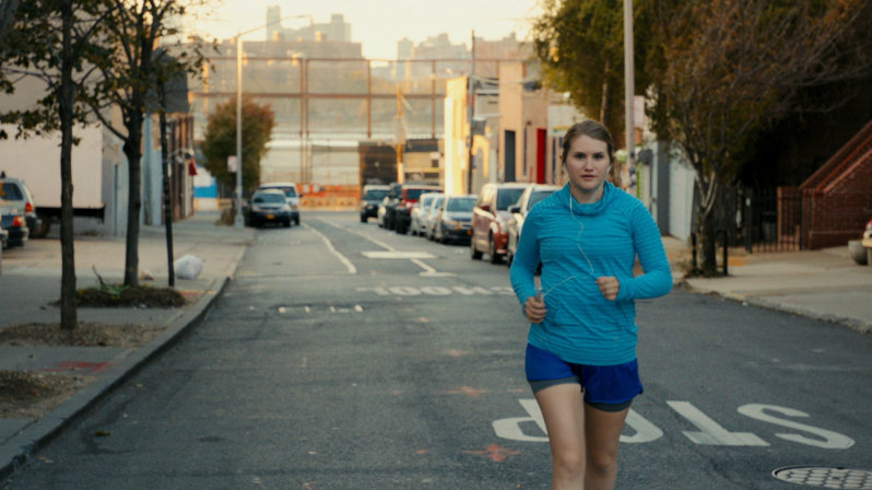 Jillian Bell running down an empty city street in workout clothes in the movie Brittany Runs a Marathon