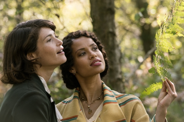 Gemma Arterton and Gugu Mbatha-Raw look at a leaf on a tree in the movie Summerland